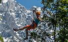 Femme glissant sur une tyrolienne en souriant